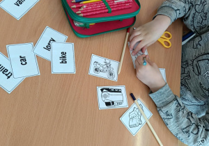 Uczniowie dopasowują flashcardy – dzieci stoją przy tablicy i dopasowują obrazki do angielskich słówek.