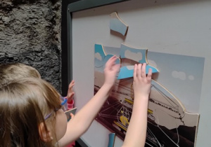 Dziewczynka układa Bełchatowskie puzzle.