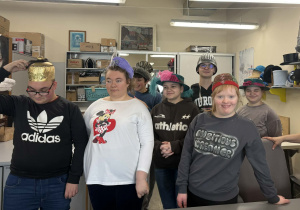 Uczniowie uczestniczący w wycieczce pozują do zdjęcia w pracowni kapeluszy.