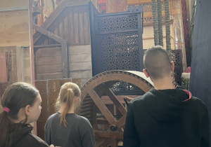 Uczniowie w magazynie dekoracji oglądają wiatrownicę.