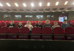 Uczniowie wcielają się w rolę widzów, siedząc w czerwonych fotelach widowni.