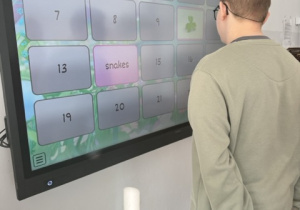 Chłopiec gra w grę memory na tablicy multimedialnej, dopasowując obrazki związane z Dniem Świętego Patryka.