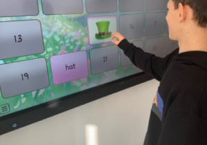 Chłopiec gra w grę memory na tablicy multimedialnej, dopasowując obrazki związane z Dniem Świętego Patryka.